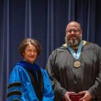 Provost Mili takes picture on stage with man